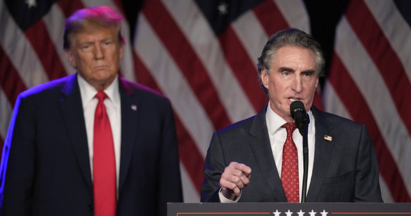 Former President Donald Trump listens as North Dakota Gov. Doug Burgum speaks at a caucus night rally in Las Vegas in a file photo dated Feb. 8.