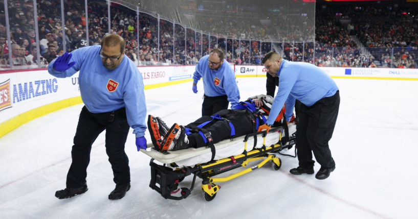 Referee Mitch Dunning, center, is stretchered off the ice after an injury during the first period of an NHL hockey game between the Philadelphia Flyers and the Colorado Avalanche, Monday, Nov. 18, 2024, in Philadelphia.