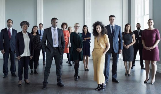 This stock image shows a diverse group of professionals in the workplace.