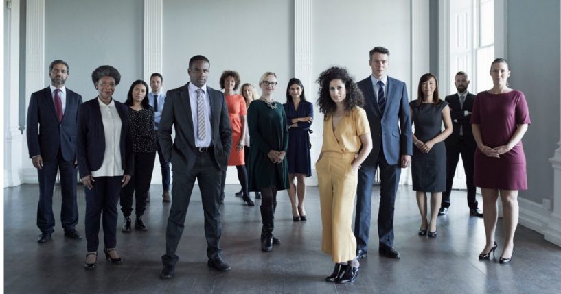 This stock image shows a diverse group of professionals in the workplace.