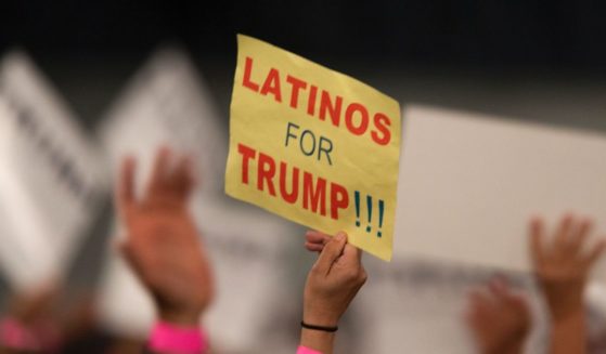 A woman holding up a "Latinos For Trump" sign at a 2016 rally in Costa Mesa, California.