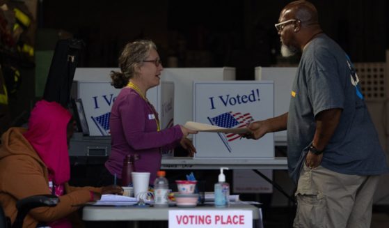 An election worker hands a ballot to a voter at a polling location inside the Pittsburgh Bureau of Fire Engine Company #15 house in Pittsburgh, Pennsylvania, on Tuesday.