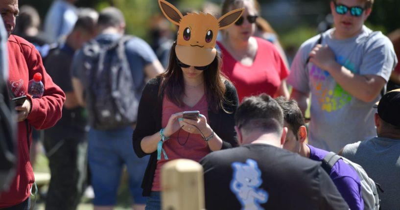 Gamers look at their phones during the Pokemon Go Festival in Westfalenpark, Germany, on July 4, 2019.