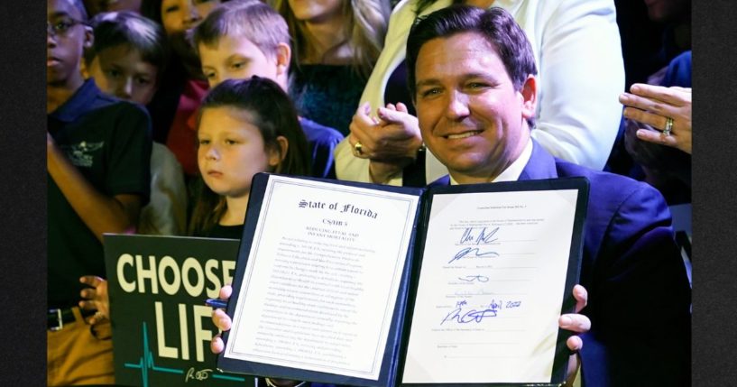 Florida Gov. Ron DeSantis holds up a 15-week abortion ban law after signing it on April 14, 2022, in Kissimmee, Florida.