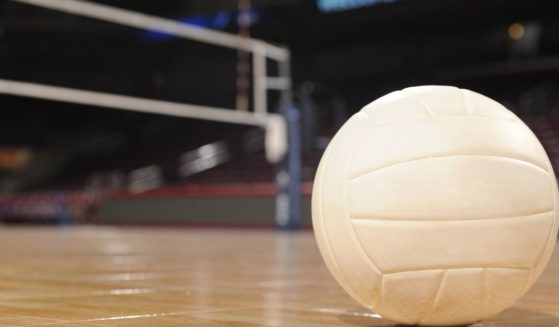 This stock image shows a volleyball sitting on an empty volleyball court.