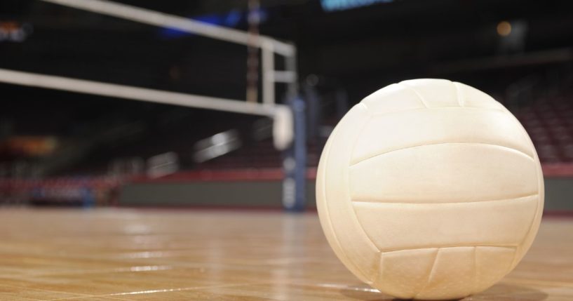 This stock image shows a volleyball sitting on an empty volleyball court.