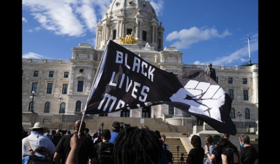 A demonstrator holds a Black Lives Matter flag outside the Minnesota State Capitol building on May 24, 2021 in St Paul, Minnesota.