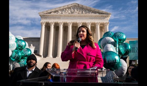 Lorie Smith, a Christian graphic artist and website designer in Colorado, center in pink, speaks to supporters outside the Supreme Court on Monday, Dec. 5, 2022 in Washington, DC.