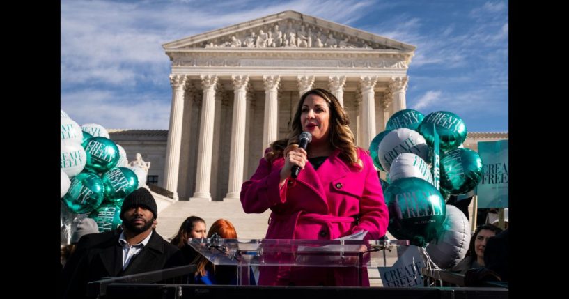 Lorie Smith, a Christian graphic artist and website designer in Colorado, center in pink, speaks to supporters outside the Supreme Court on Monday, Dec. 5, 2022 in Washington, DC.