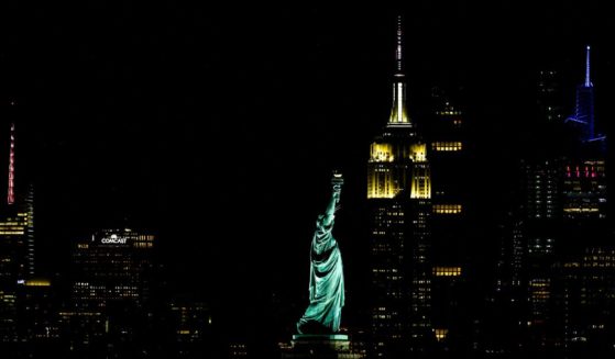 The iconic Empire State Building stands out on the Manhattan skyline with The Statue of Liberty in the foreground, seen at night from Bayonne, New Jersey, on August 1, 2024.