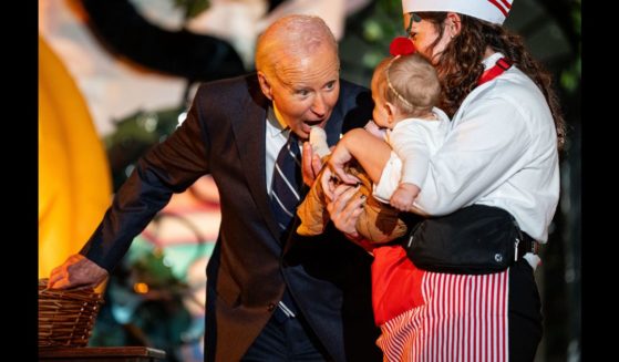 US President Joe Biden tries to bite a baby as he and first lady Jill Biden greet trick-or-treaters during a Halloween event at the White House on October 30, 2024 in Washington, DC.