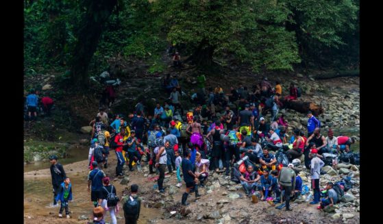 Migrants, mostly from Ecuador, Haiti and Nigeria, pause for a break before climbing a muddy hillside trail in the wild and dangerous jungle on November 20, 2022 in Darién Gap, Colombia.