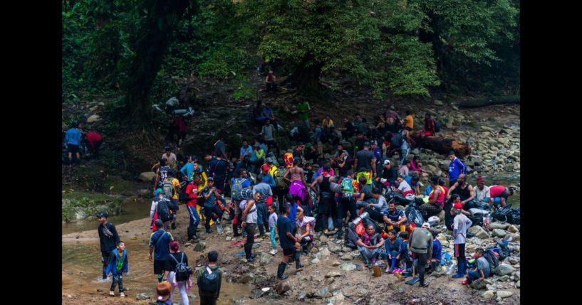 Migrants, mostly from Ecuador, Haiti and Nigeria, pause for a break before climbing a muddy hillside trail in the wild and dangerous jungle on November 20, 2022 in Darién Gap, Colombia.