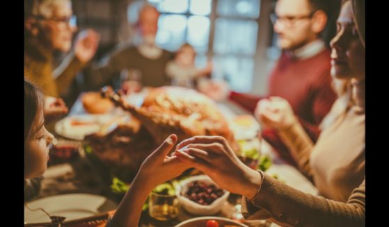 This Getty stock image shows a family praying around a Thanksgiving feast.