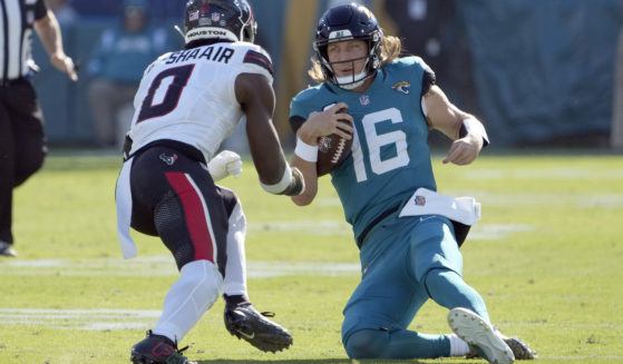 Jacksonville Jaguars quarterback Trevor Lawrence, right, slides in front of Houston Texans linebacker Azeez Al-Shaair, left, during the first half of an NFL football game in Jacksonville, Florida, on Sunday.