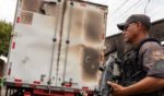 A policeman stands guard next to a burnt commercial truck in Natal, Rio Grande do Norte state, Brazil on 16 March 2023.