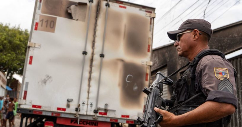 A policeman stands guard next to a burnt commercial truck in Natal, Rio Grande do Norte state, Brazil on 16 March 2023.