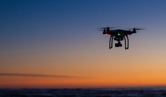 This stock image shows a drone flying over the ocean at sunrise.