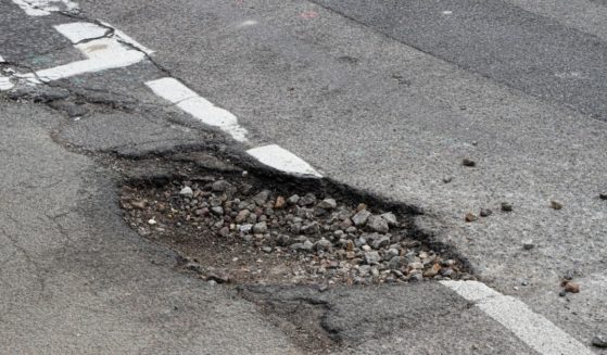 A pothole is pictured on a road that already had previous repairs done.