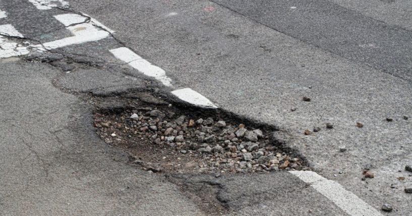 A pothole is pictured on a road that already had previous repairs done.