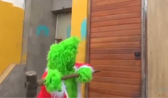 This X screen shot shows a Peruvian police officer dressed as the Grinch taking a sledgehammer to the door of suspected criminals.