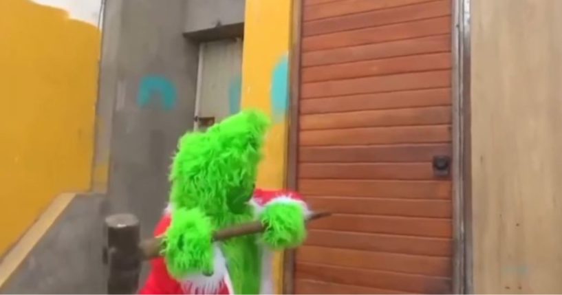 This X screen shot shows a Peruvian police officer dressed as the Grinch taking a sledgehammer to the door of suspected criminals.