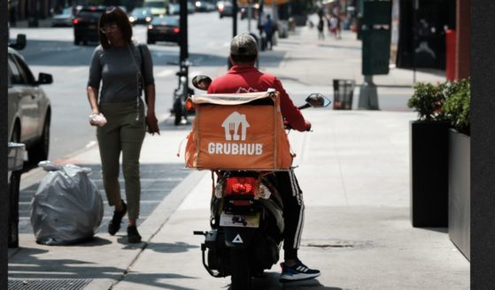 A driver for app-based delivery service Grubhub waits outside a New York City restaurant in a file photo from July 2023.