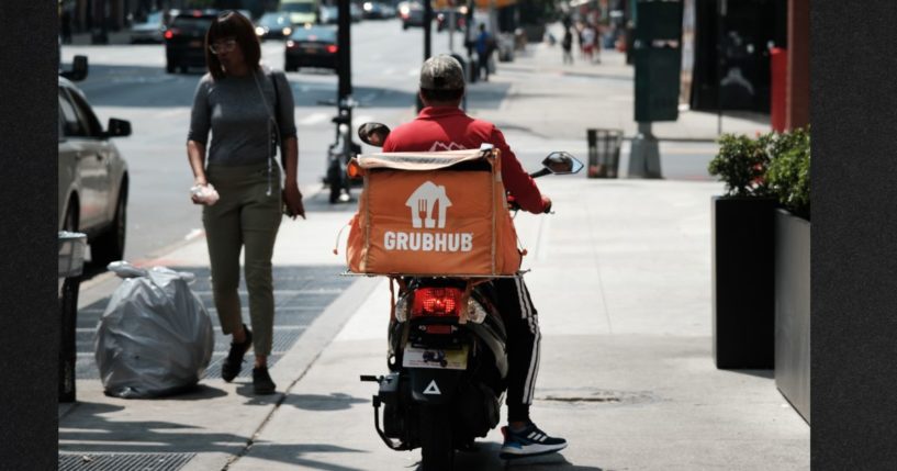 A driver for app-based delivery service Grubhub waits outside a New York City restaurant in a file photo from July 2023.