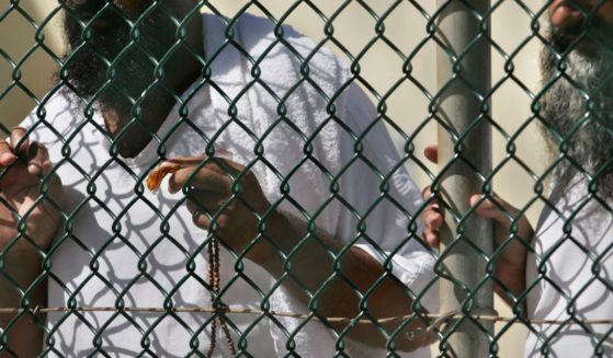 Detainees stand together at a fence, one holding Islamic prayer beads, at Camp Delta prison, at the Guantanamo Bay U.S. Naval Base, Cuba, in a file phot from September 2006. The Biden administration transferred a Tunisian prisoner to his home country this week, the Pentagon announced.