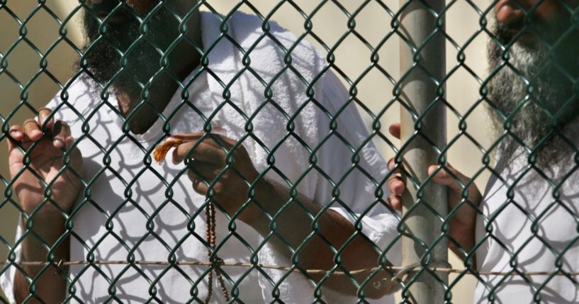 Detainees stand together at a fence, one holding Islamic prayer beads, at Camp Delta prison, at the Guantanamo Bay U.S. Naval Base, Cuba, in a file phot from September 2006. The Biden administration transferred a Tunisian prisoner to his home country this week, the Pentagon announced.