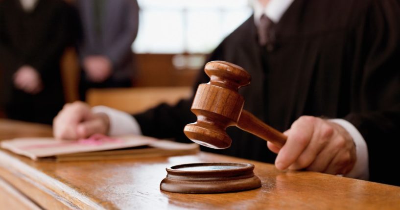 This stock image shows a judge banging his gavel in a courtroom.