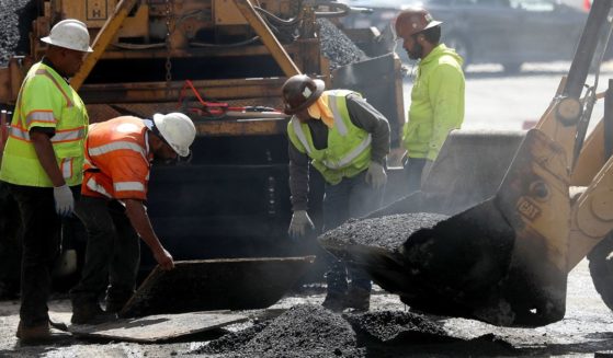 Construction workers smooth tar as they pave a road on October 5, 2018 in San Francisco, California.