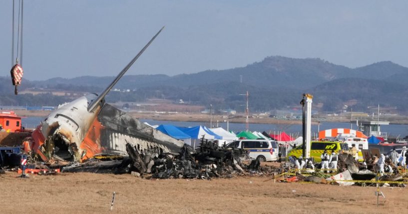 Rescue team members work at the site of a plane fire at Muan International Airport in Muan, South Korea, on Monday.