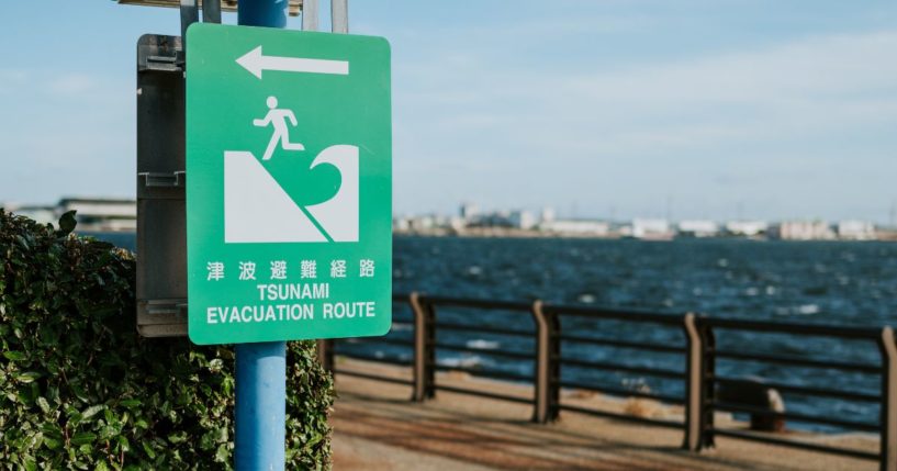 A tsunami evacuation sign is posted on a beach.