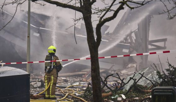 A firefighter hoses down rubble after a blast ripped through the Hague.