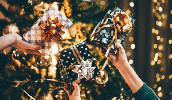 This Getty stock image shows a trio of hands each holding a wrapped Christmas gift.