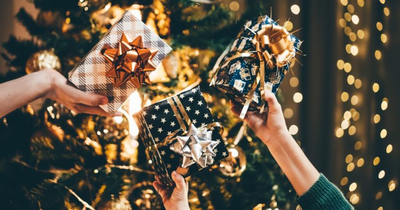 This Getty stock image shows a trio of hands each holding a wrapped Christmas gift.