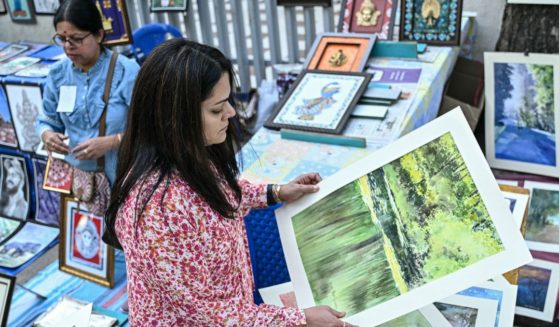 A visitor looks at paintings on display for sale at a roadside stall during "Chitra Santhe," a day-long annual art carnival organised by Chitrakala Parishath, in Bengaluru, India, on January 5, 2025.