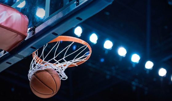 This stock image shows a basketball going through the hoop.