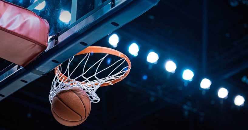 This stock image shows a basketball going through the hoop.