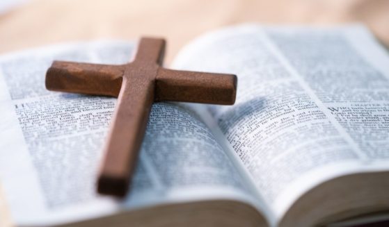 This stock image shows a cross resting on top of an open Bible.