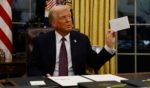 President Donald Trump holds up a letter from former President Joe Biden found in the Resolute desk in the Oval Office of the White House in Washington, D.C., on Monday.