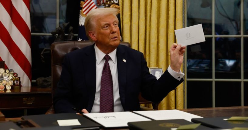 President Donald Trump holds up a letter from former President Joe Biden found in the Resolute desk in the Oval Office of the White House in Washington, D.C., on Monday.