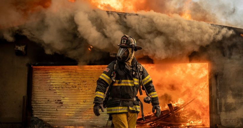 A firefighter works to put out a fire at the Altadena Golf Course in Altadena, California, on Thursday.