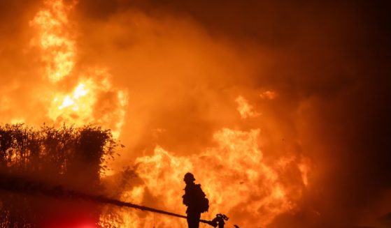 A firefighter stands on top of a fire truck to battle the Palisades Fire while it burns homes on the Pacific Coast Highway amid a powerful windstorm Los Angeles, California, on Jan. 8.