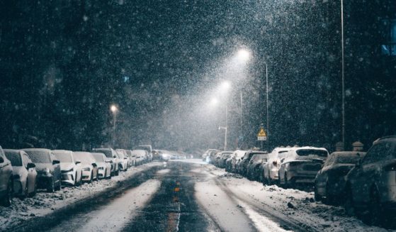 This stock image shows snow falling on a street at night.