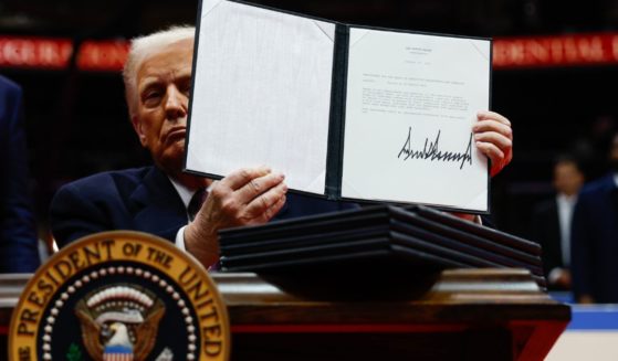 President Donald Trump holds up one of several executive orders signed at the Capitol One Arena in Washington, D.C., on Monday.