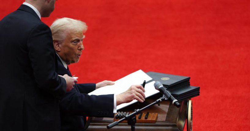 President Donald Trump signs executive orders during an indoor inauguration parade at Capital One Arena in Washington, D.C., on Monday.