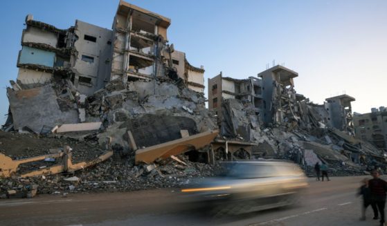 Pedestrians and cars pass by apartments destroyed by Israeli army strikes in the central Gaza Strip town of Khan Younis Wednesday. One such strike killed a Hamas leader who commanded a battalion that slaughtered dozens of civilians in the Israeli Kibbutz Nir Oz on Oct. 7, 2023