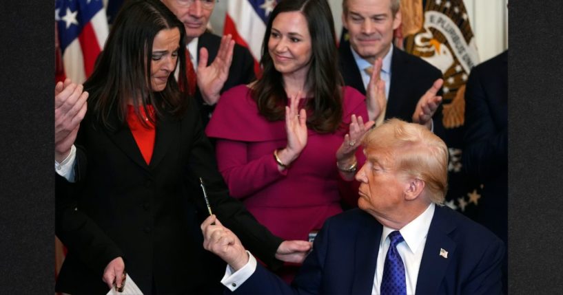 President Donald Trump hands a pen to Allyson Phillips, mother of Laken Riley, after signing the Laken Riley Act in the East Room of the White House, Wednesday in Washington.